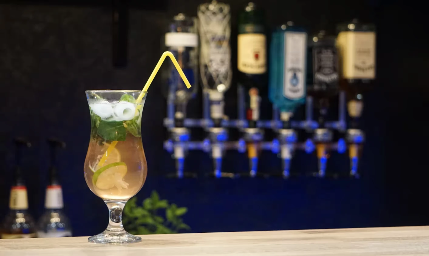 cocktail on a bar counter with beverages on a shelf as background